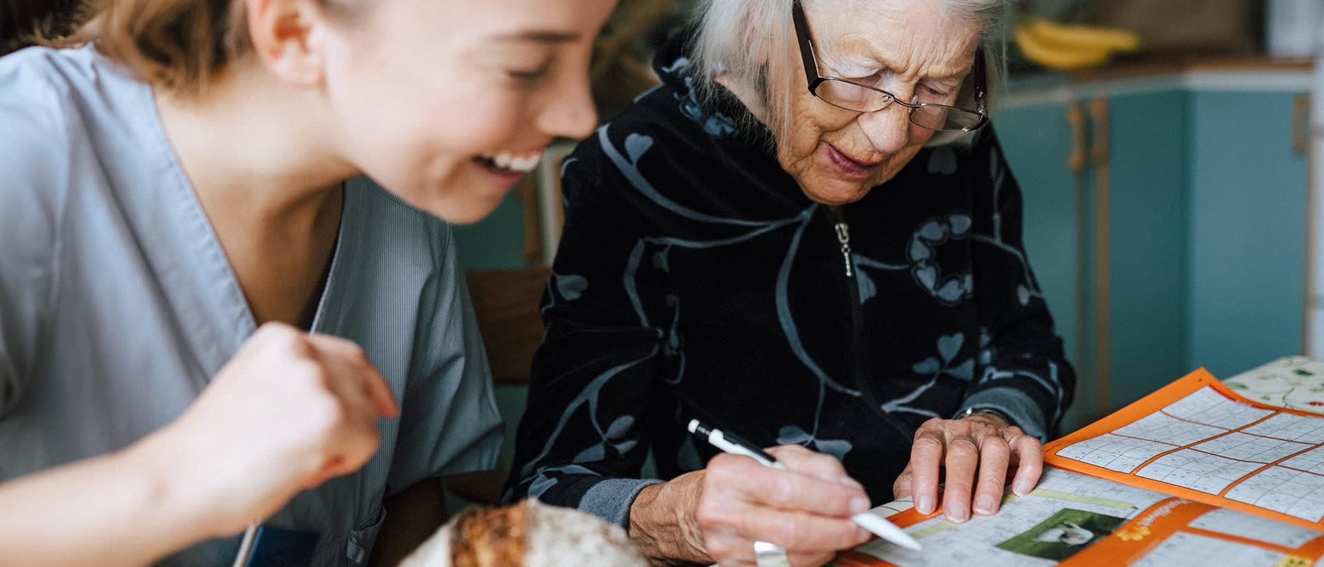Bild på en tjej och en äldre kvinna som löser korsord.