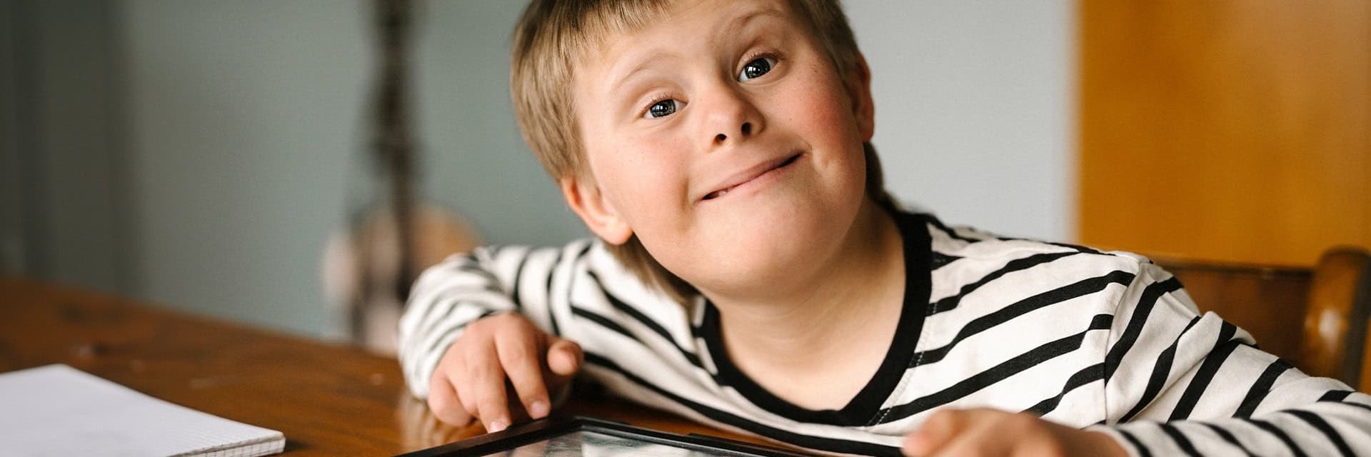 Ett bild på en pojke med Downs syndrome som sitter vid ett bord.