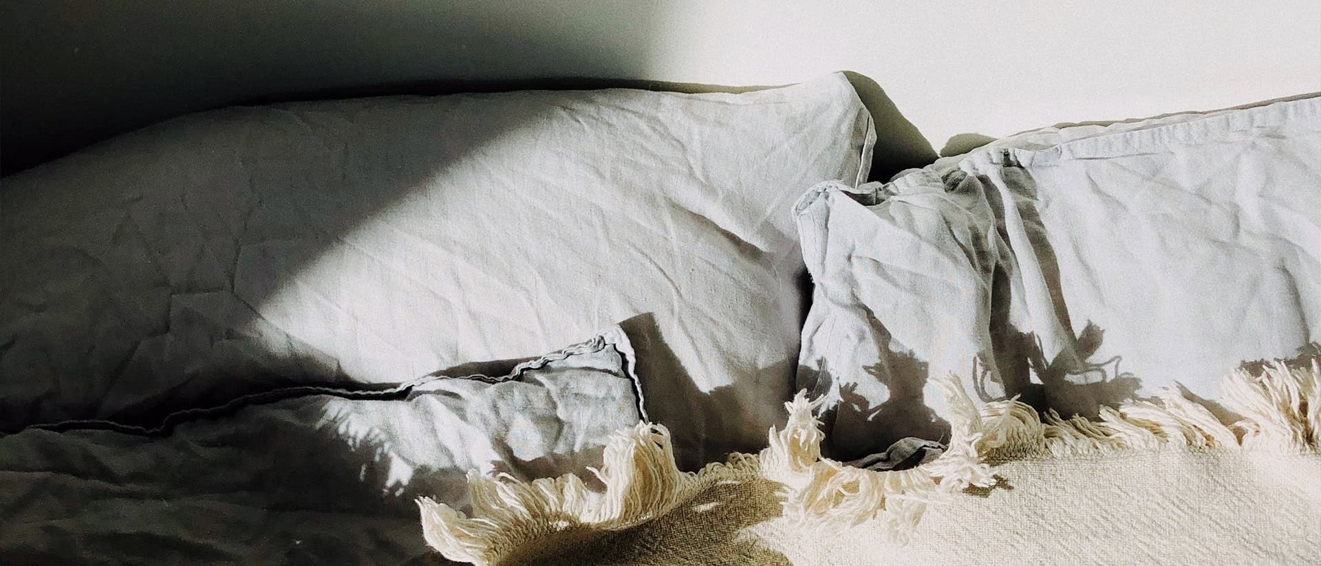 Foto på en säng med kuddar och täckte.