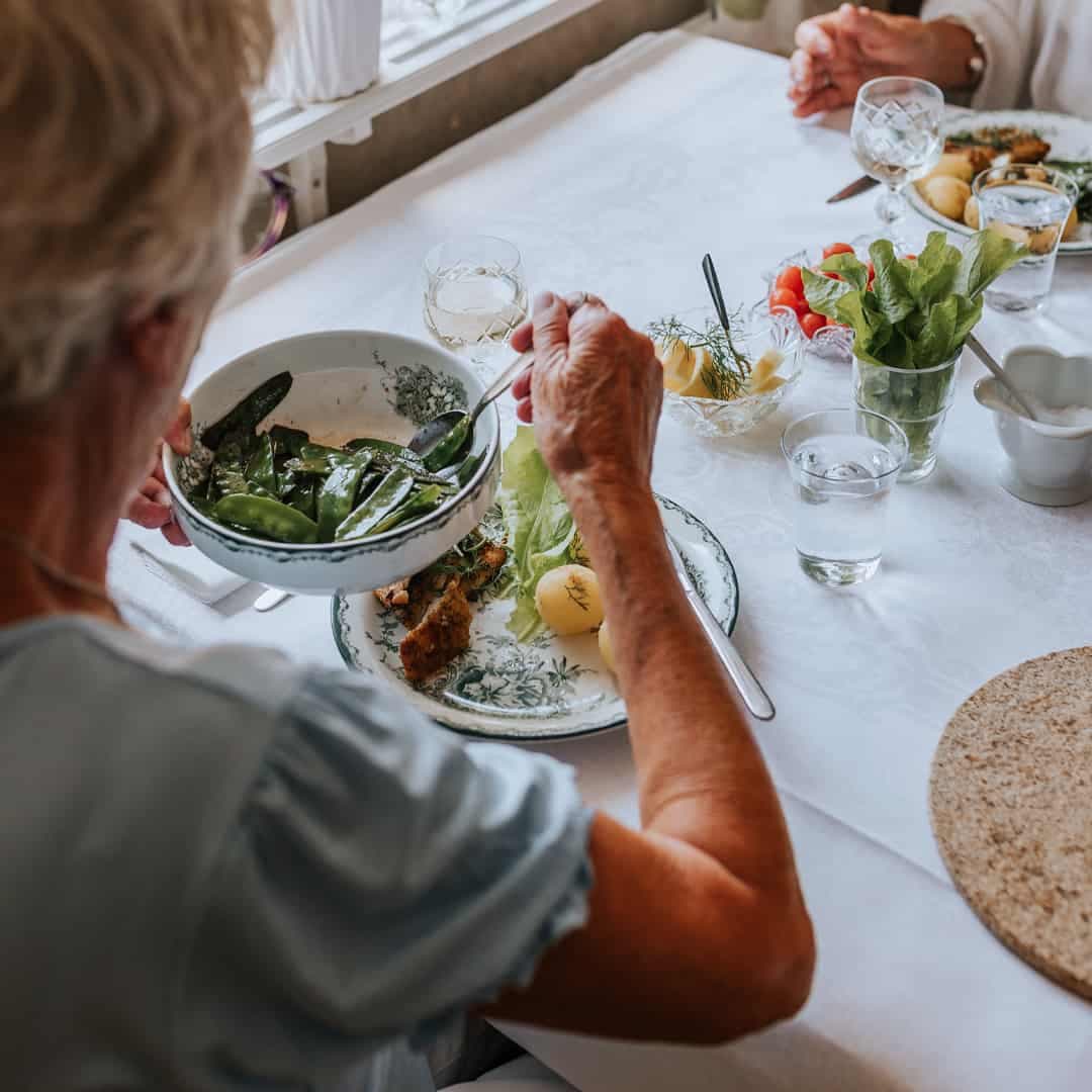 Äldre personer äter tillsammans vid ett dukat bord.