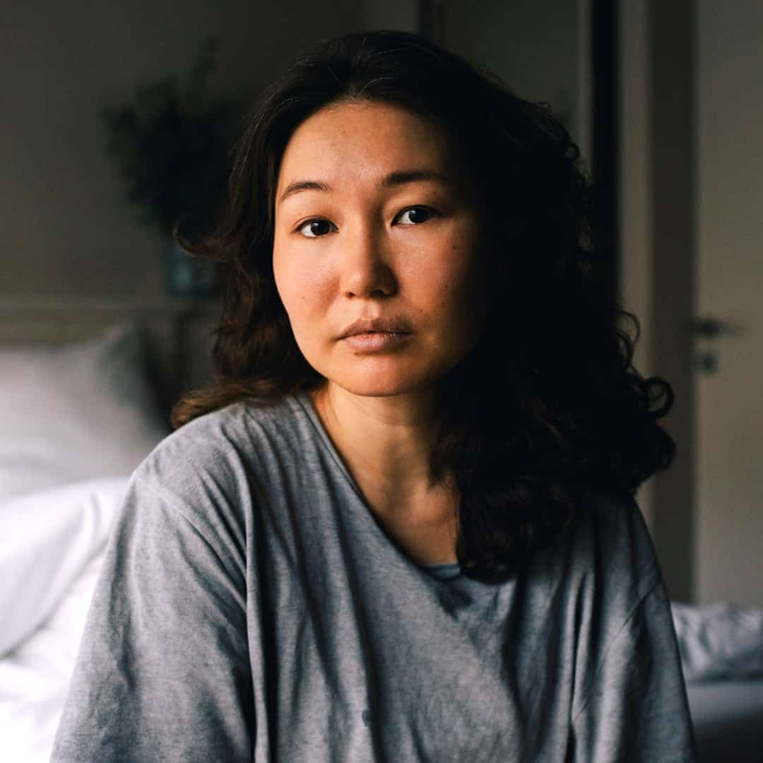 Porträtt på en kvinna som sitter på en säng.