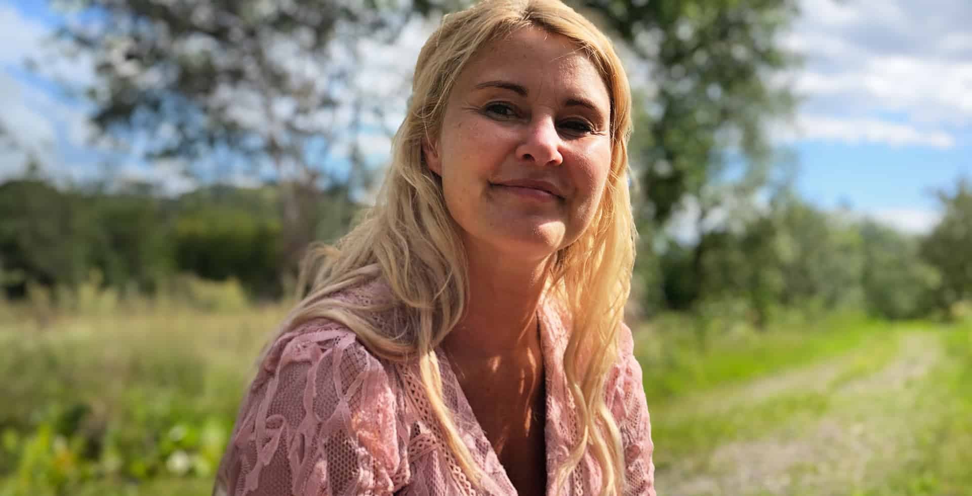 Porträtt av Johanna sittandes utomhus i solen.